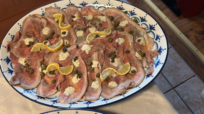 Ein Teller mit mariniertem Fisch, garniert mit Zitrone und Kräutern.